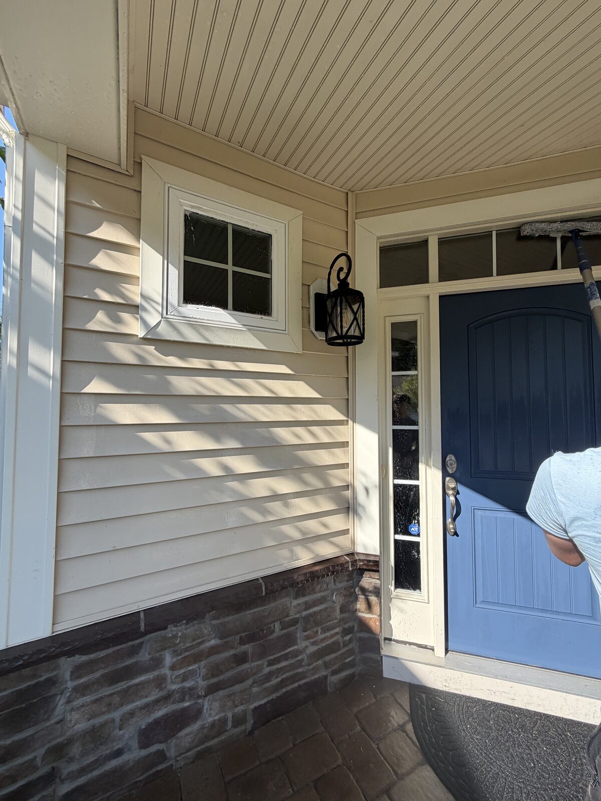 Technician washing transom glass above a front door