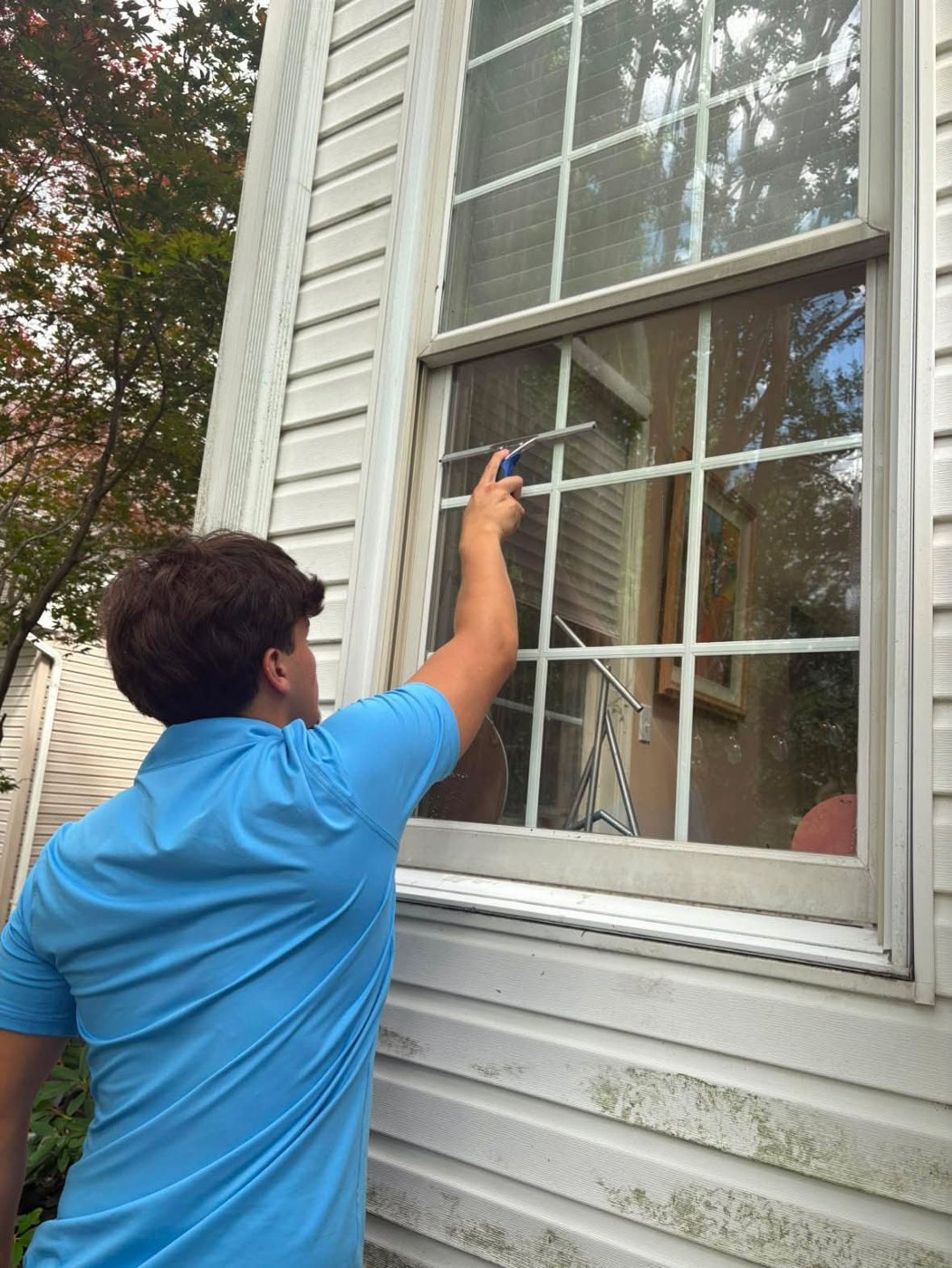 Legacy technician squeegeeing a second-story window